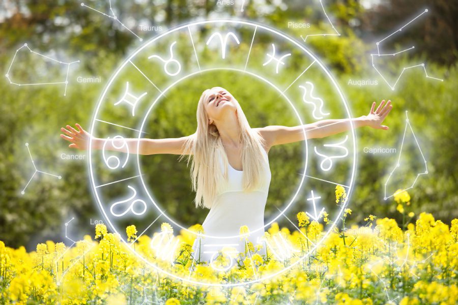 Woman in field with zodiac signs overlay.