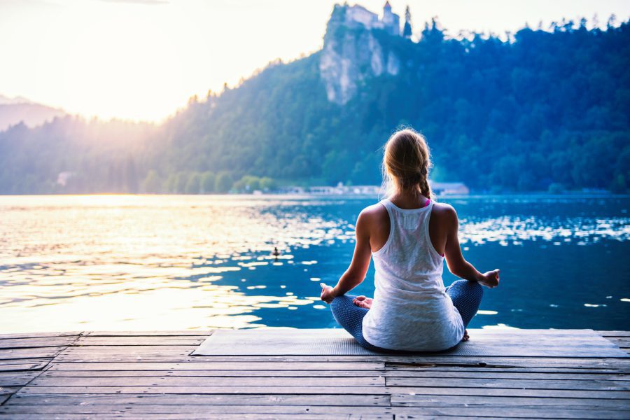 Person meditating by a serene lakeside.