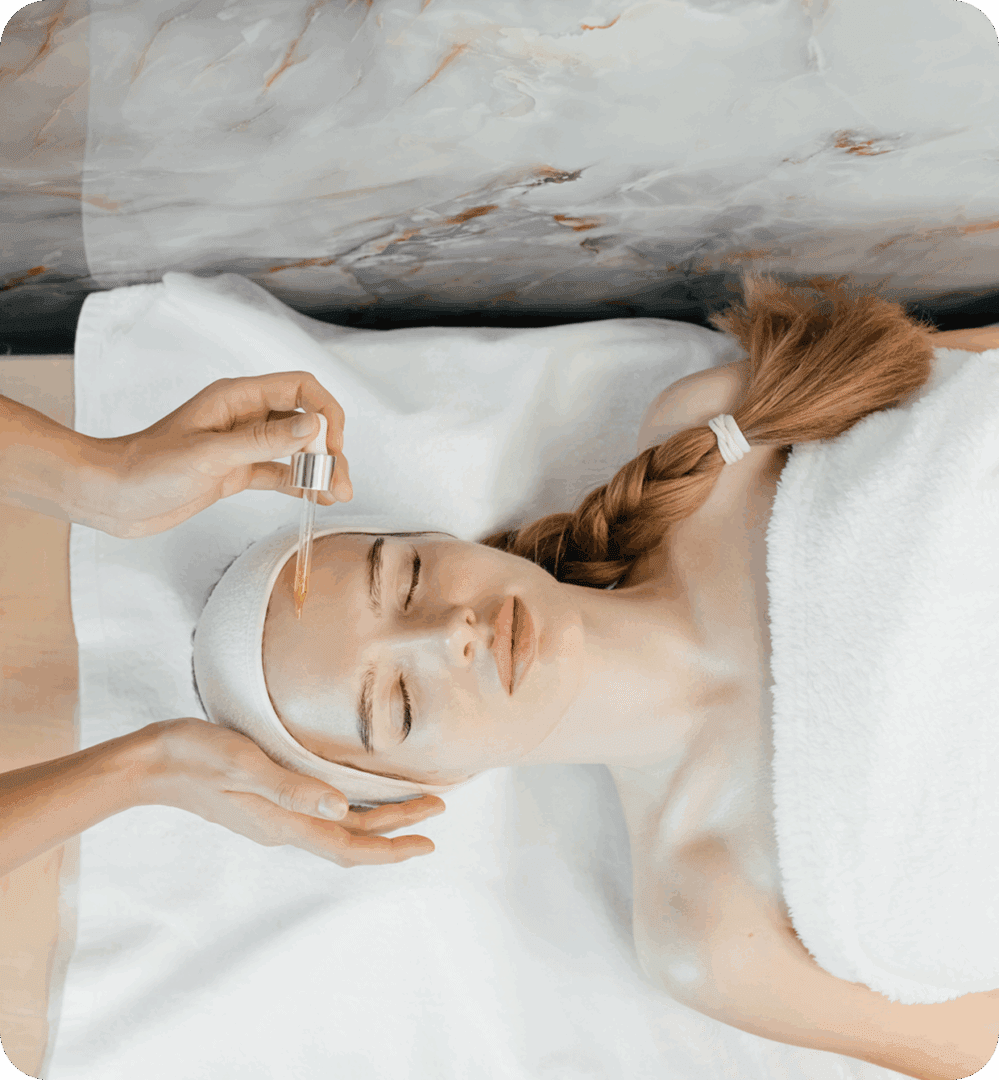 Woman receiving facial treatment with serum dropper.