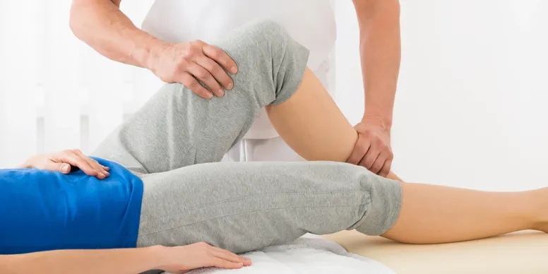 Physical therapist assisting patient with knee exercise.