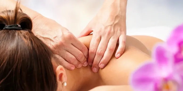 Hands performing a neck massage on a person.