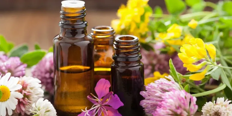Brown glass bottles with essential oils and colorful flowers.