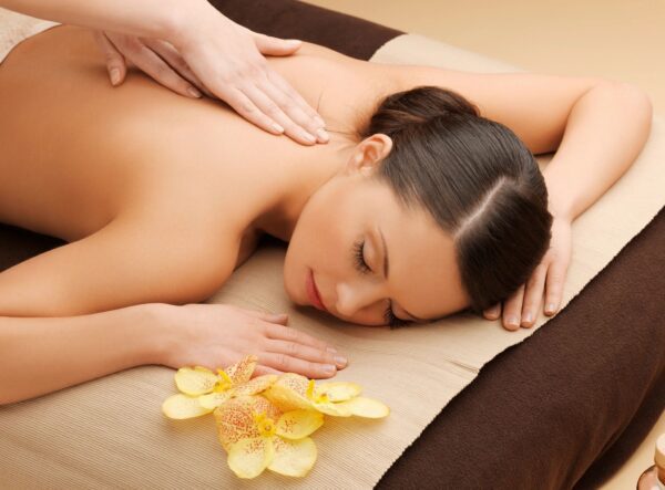A woman enjoying a relaxing back massage with flowers nearby.