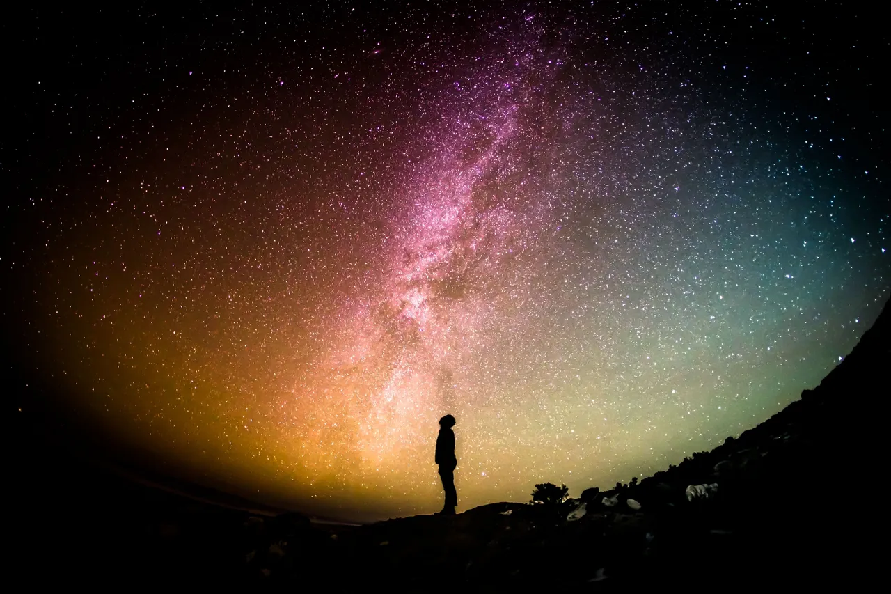 Silhouette of a person under the colorful Milky Way galaxy.