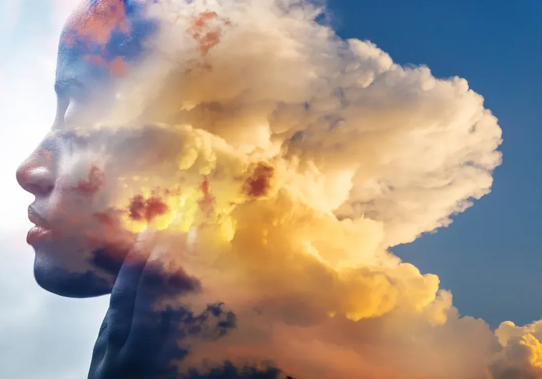 A towering cloud illuminated by golden sunlight against a blue sky.