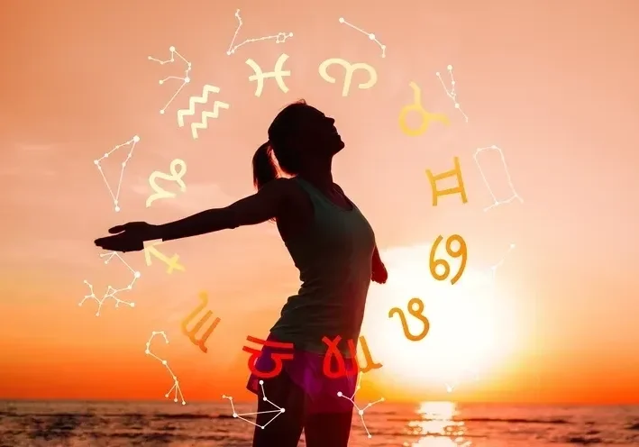 Silhouette of a person embracing the sunset with zodiac signs above.